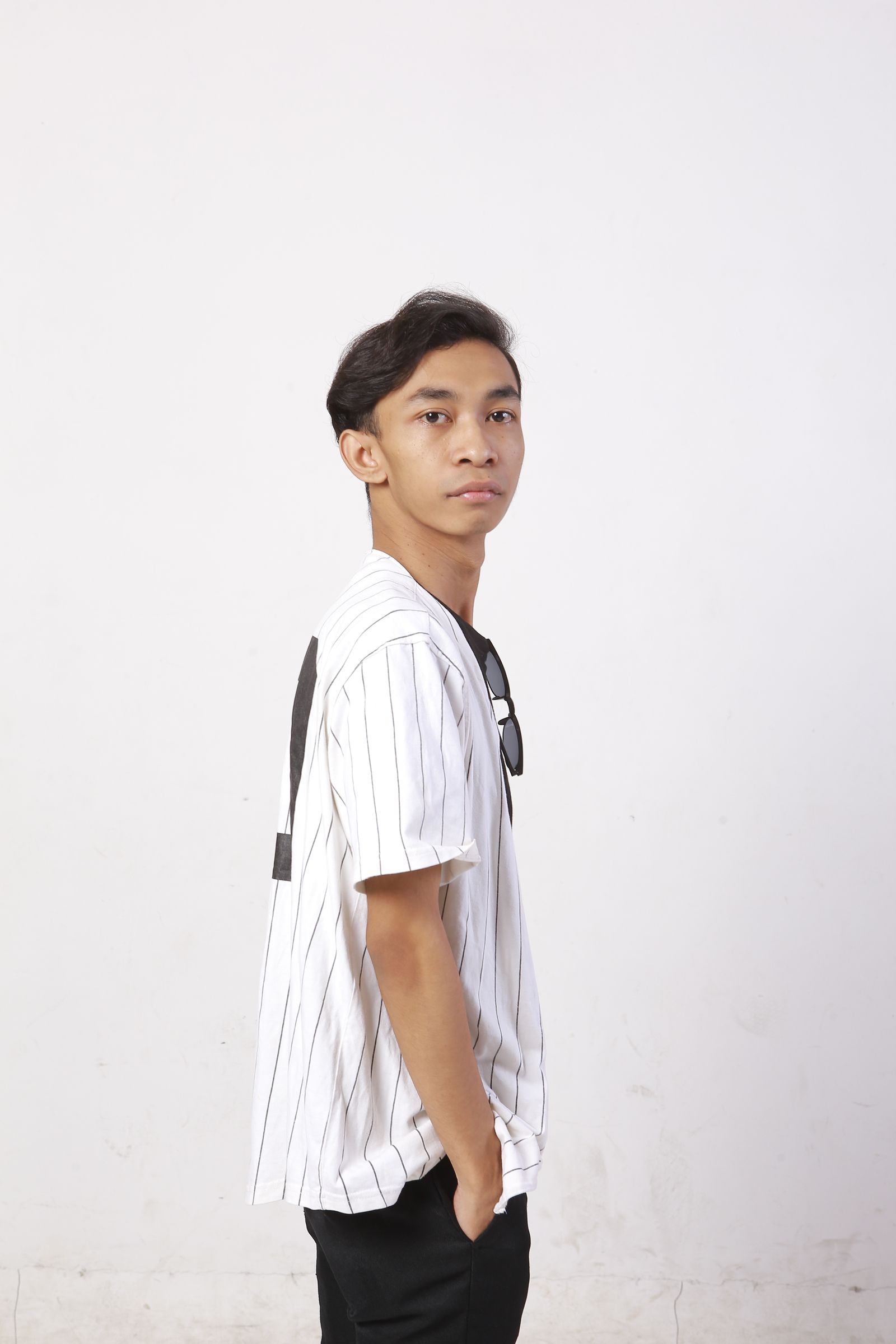 Starzgrey standing in a striped shirt against a white wall